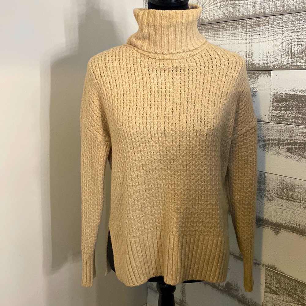 Knitted tan colored turtleneck sweater.